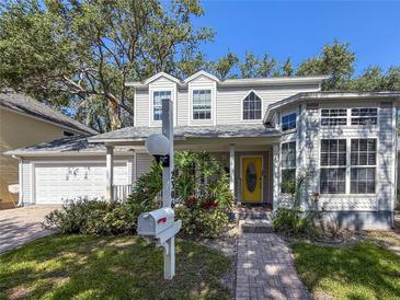 Charming two-story home features a welcoming yellow door, lush landscaping, and classic architectural details at 2306 63Rd W St # 40, Bradenton, FL 34209