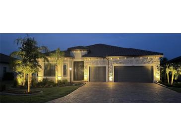 Beautifully illuminated home featuring a stone facade, tile roof, and two-car garage at 7327 Summerland Cv, Bradenton, FL 34202