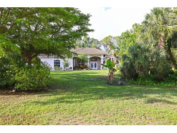Charming home featuring a well-manicured lawn and lush, mature landscaping at 950 Trotter St, Nokomis, FL 34275
