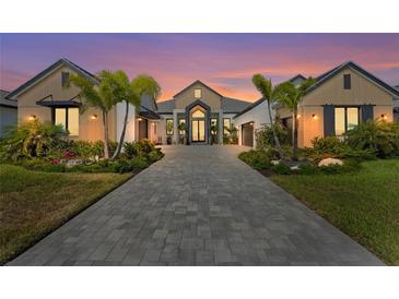 Stunning home exterior featuring lush landscaping, palm trees, brick driveway, and architectural design at sunset at 1182 Blue Shell Loop, Sarasota, FL 34240