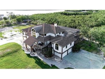Stunning two-story home featuring a screened-in pool, lush landscaping, and a beautiful outdoor entertainment area near the waterfront at 2400 Miguel Bay Dr, Terra Ceia, FL 34250