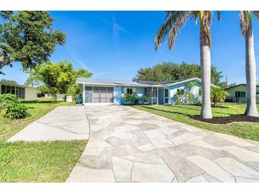 Charming one-story home with a light blue exterior, a patterned driveway and tropical landscaping at 3585 Brooklyn Ave, Port Charlotte, FL 33952