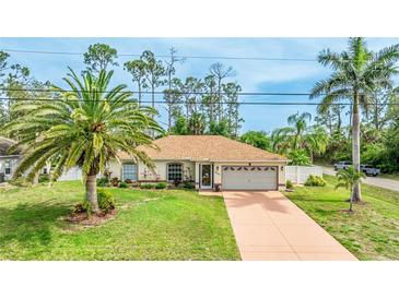 Charming single-story home with a well-maintained lawn, palm trees, and a two-car garage at 5307 Kenvil Dr, North Port, FL 34288