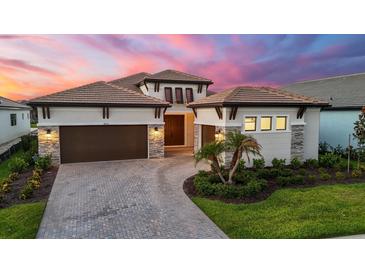 Elegant home featuring a well-manicured lawn, paver driveway, and a three-car garage at 8962 Baroque Ter, Sarasota, FL 34240