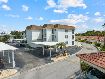 Condominium complex with white walls, brown roofs, covered parking and well manicured landscaping at 110 Vista Hermosa Cir # 302B, Sarasota, FL 34242