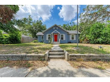 Charming blue home featuring a bright red door, well-maintained lawn, and classic architectural details at 2509 8Th W Ave, Bradenton, FL 34205