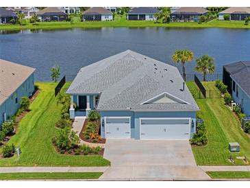 Beautiful blue home with a gray roof, two-car garage, and a picturesque lake view in the backyard at 4407 Big Woods Way, Parrish, FL 34219