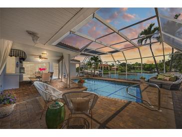 Relaxing screened pool with dining area and waterfront views at dusk at 572 Commonwealth Ln, Sarasota, FL 34242