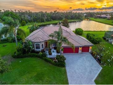 Beautiful waterfront home featuring a tile roof, lush landscaping, and a three-car garage at sunset at 312 148Th Ne Ct, Bradenton, FL 34212