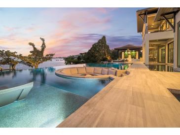 Custom infinity pool with a fire pit and lounge seating overlooking the waterway at dusk at 3799 Flamingo Ave, Sarasota, FL 34242