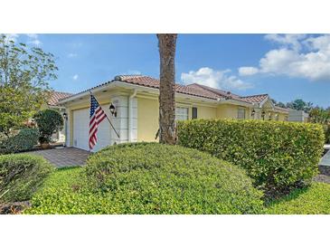 Charming home exterior with a red tile roof, American flag, and well-maintained landscaping at 5566 Avellino Pl, Sarasota, FL 34238