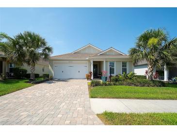Beautiful single-story home with paver driveway, two-car garage, and lush tropical landscaping at 8077 Sandstar Way, Sarasota, FL 34240