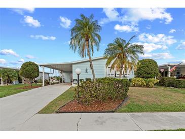Charming light blue home with manicured lawn and tropical palm trees under a bright blue, partly cloudy sky at 8531 Imperial Cir, Palmetto, FL 34221