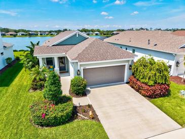 Beautiful single-story home featuring lush landscaping, an attached two-car garage, and scenic water views at 13849 Old Creek Ct, Parrish, FL 34219