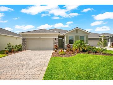Charming one-story home showcasing a landscaped front yard and brick driveway under a bright, partly cloudy, blue sky at 18317 Gulf Ranch Pl, Bradenton, FL 34211