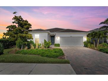 Charming single-story home with a well-manicured lawn, brick driveway, and a two-car garage at 26000 Seastone Dr, Englewood, FL 34223