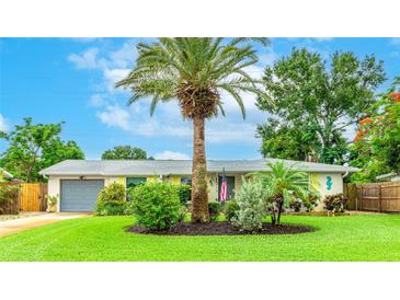 Charming single-story home with a well-manicured lawn, a palm tree, and a gray garage at 5603 1St Avenue Dr Nw, Bradenton, FL 34209