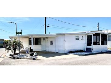 Charming manufactured home with bright white siding, carport, and a cozy screened-in porch in a lovely neighborhood at 72 4Th Ave # 72, Venice, FL 34285