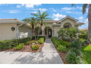 Charming home featuring a tiled roof, black front door, and lush landscaping with palm trees and colorful flowers at 9635 Discovery Ter, Bradenton, FL 34212