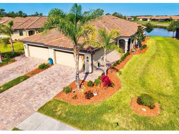 Stunning home featuring lush landscaping, brick driveway, and a three-car garage at 12230 Amica Loop, Venice, FL 34293