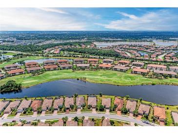 Stunning aerial view of a golf course community, featuring homes, lakes, and lush green fairways under a sunny sky at 13711 Messina Loop # 102, Lakewood Ranch, FL 34211