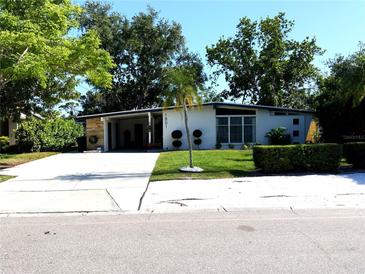 Charming single-story home with a well-manicured lawn and modern design, featuring mature trees and a spacious driveway at 1801 Marilyn Ave, Bradenton, FL 34207