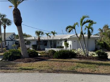 Inviting single-story home features a manicured lawn with palm trees and white exterior at 191 Maria Ct, Punta Gorda, FL 33950