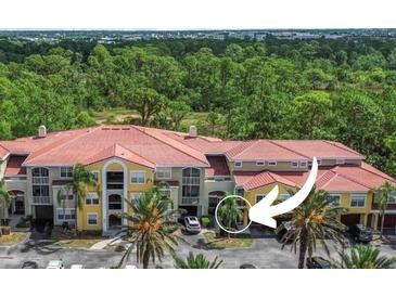 Condo building featuring colorful siding, a red tile roof, and lush landscaping at 5401 Bentgrass Dr # 1-113, Sarasota, FL 34235