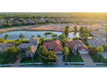 Aerial view of a beautiful home with a tile roof, situated on a golf course with a scenic lake view at 6914 Dominion Ln, Lakewood Ranch, FL 34202