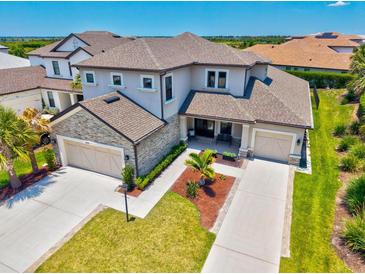 Stunning two-story home with a stone-accented facade, lush landscaping, and a spacious three-car garage at 8272 Summer Night Rd, Sarasota, FL 34241