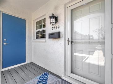 Inviting front entrance with blue door, decorative rug, and charming exterior lighting, enhancing curb appeal at 9822 Desoto Ct, Bradenton, FL 34210