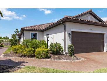 Charming home with tile roof, lush landscaping, and brick paver driveway at 15752 Sacile Ln, Bradenton, FL 34211