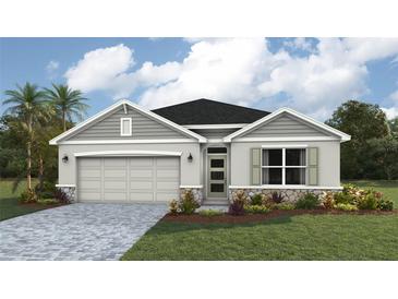 Inviting single-story home with a two-car garage, stone accents, well-manicured lawn, and lush landscaping at 1758 Cobb Trl, Parrish, FL 34219