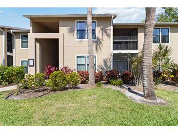 Beautiful condo exterior featuring lush landscaping with green grass, plants, and palm trees at 4061 Crockers Lake Blvd # 27, Sarasota, FL 34238