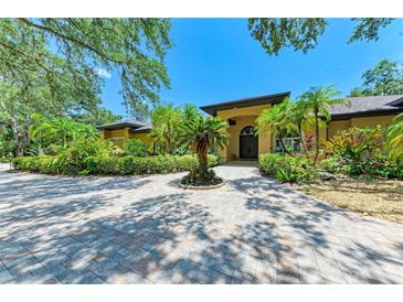 Stunning home featuring lush landscaping, mature trees, and a circular paver driveway at 4647 Stone Ridge Trl, Sarasota, FL 34232