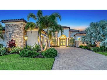 Stunning exterior view of home with lush landscaping, stone accents, and arched entryway at twilight at 4809 Benito Ct, Bradenton, FL 34211