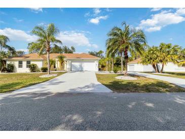 Charming single-story home with well-manicured lawn, palm trees, and long driveway leading to a two-car garage at 5266 Wagon Wheel Dr, North Port, FL 34291