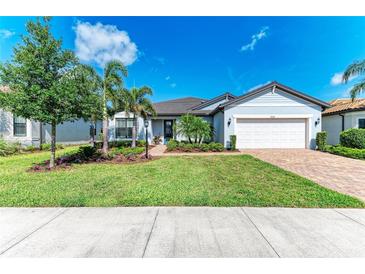 Beautiful single-story home featuring a well-manicured lawn, mature trees, and a two-car garage at 7136 Summerland Cv, Bradenton, FL 34202