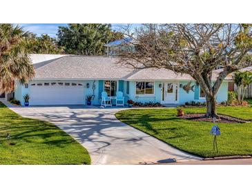 Charming light blue home with a well manicured lawn, curved driveway and welcoming front porch with blue seating at 7817 Alhambra Dr, Bradenton, FL 34209