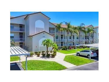 Exterior view of building featuring well-maintained landscaping and covered parking on a bright, sunny day at 8755 Olde Hickory Ave # 7107, Sarasota, FL 34238