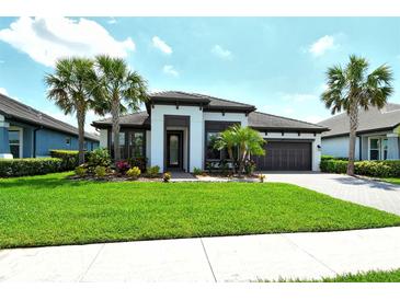 Beautiful single-story home with tropical landscaping, well-manicured lawn, and a two-car garage at 1919 Woodleaf Hammock Ct, Bradenton, FL 34211
