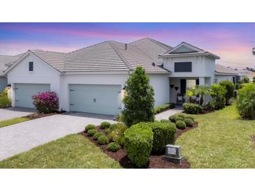 Charming home exterior featuring lush landscaping, a brick driveway, and a serene color palette at 2631 Sapphire Blue Ln, Bradenton, FL 34211