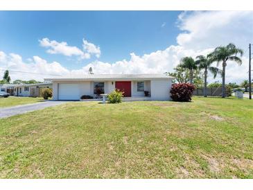 Single-story home featuring a bright red front door and well-manicured front yard with mature trees at 4535 Maceachen Blvd, Sarasota, FL 34233