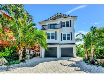 Inviting three-story beach house with a balcony and lush tropical landscaping at 5219 Calle Menorca, Sarasota, FL 34242