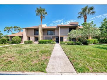 Inviting condo with a lush green lawn and mature palm trees against a bright blue sky at 933 Sunridge Way # B5, Sarasota, FL 34234