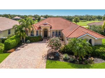 Beautiful home featuring a red tile roof, manicured landscaping and a brick paver driveway on a sunny day at 9719 Discovery Ter, Bradenton, FL 34212