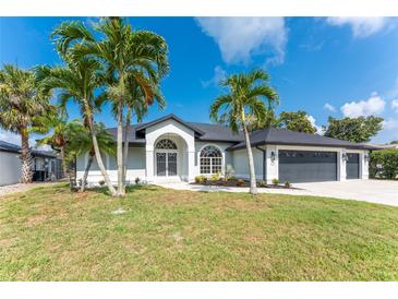 Charming single-story home featuring a manicured lawn and palm trees against a clear blue sky at 10055 Franklin Dr, Englewood, FL 34224