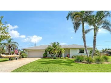 Charming single-story home featuring a lush green lawn, tropical landscaping, and an attached two-car garage at 1334 De Prie Rd, Englewood, FL 34223