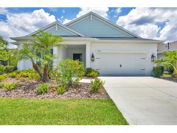 Charming single-story home features a two-car garage and meticulously landscaped front yard with palm trees at 13549 Old Creek Ct, Parrish, FL 34219