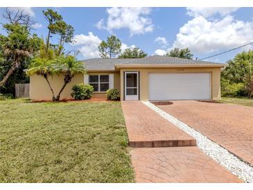 Charming single-story home with a well-maintained lawn, brick driveway, and a two-car garage at 3698 N Chamberlain Blvd, North Port, FL 34286